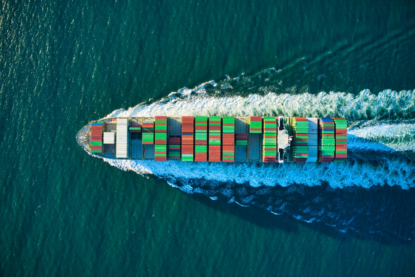 Cargo ship in teal water representing global sourcing and logistics coordination